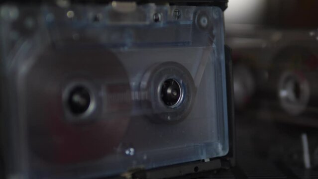 close-up of a vintage cassette in a tape recorder plays music. cassette player with old transparent film cassette. audio equipment of the 80s