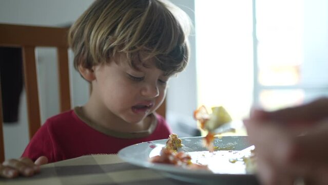 Small boy spitting food out during lunch time. Child not wanting food, feeling disgust