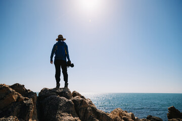 Obraz premium Woman photographer enjoy the view on sunrise seaside rocks