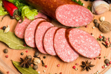 Slicing smoked sausage with spices, garlic and hot pepper on a wooden cutting board