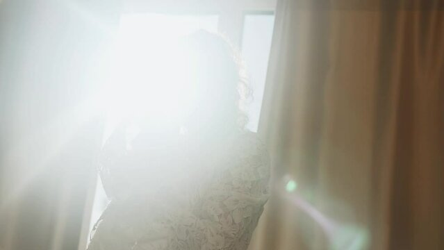 A fashion model in a wedding dress poses in a room with smoke and sunlight. Concept for fashion wedding photography