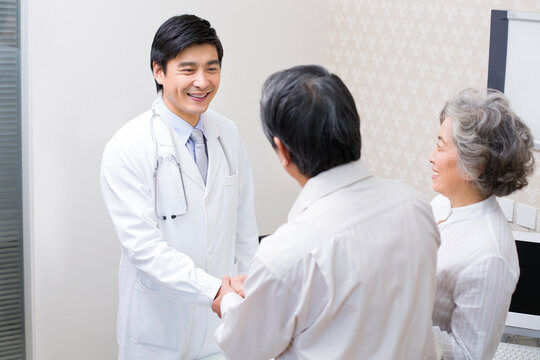 Senior couple shaking hands with doctor in hospital - Powered by Adobe