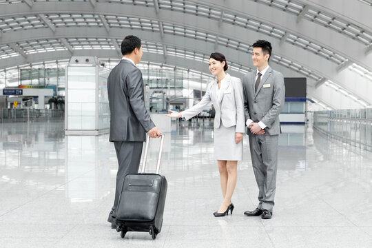Airport staff members welcoming passenger in airport lobby