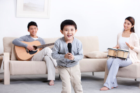 Merry young family playing musical instruments and singing at home
