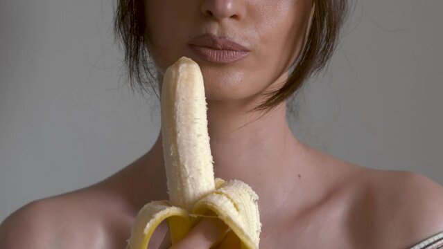 Close-up female lips eating peeled banana