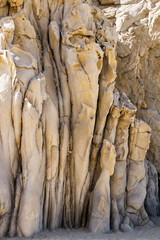 Rocks of unusual tubular shape near the sandy shore.. Cabo San Lucas, Mexico. Vertical image.