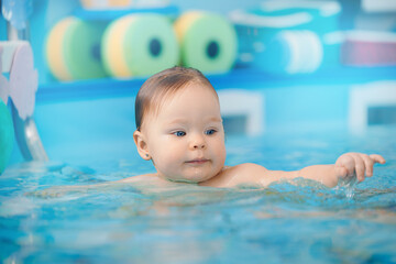 Fototapeta na wymiar Portrait happy baby girl in swimming pool, teaching small swimmer. Concept healthcare sport for infant