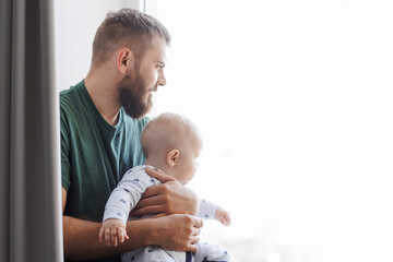 Father hugs baby boy son in living room. Concept lifestyle parenting fatherhood moment - obrazy, fototapety, plakaty