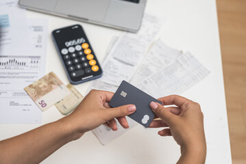 Online Utility Settlement: A woman holds her credit card near a laptop to make quick payments for communal utilities through an online system. 