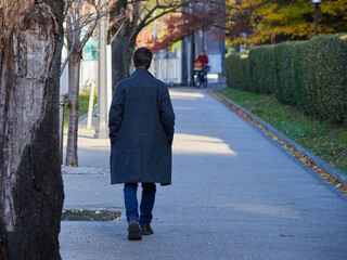 秋の都市の街の道路で散歩する一人の男性