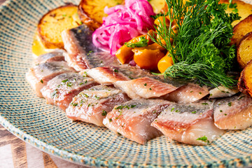 fish herring fillet with potatoes, nushrooms and onions on plate
