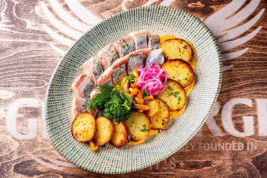 fish herring fillet with potatoes, nushrooms and onions on plate