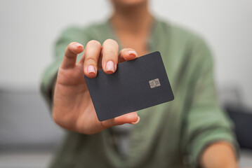Lady hand shows dark credit card with chip for contactless payment close up. online shopping mobile...