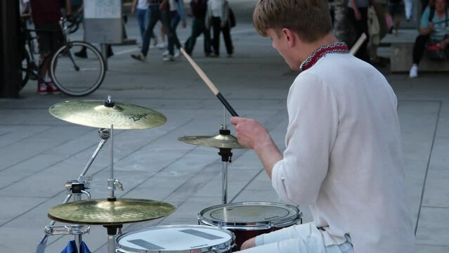 masterfully play the drum beautiful young guy of European appearance in Ukrainian embroidered shirt national clothes of Ukraine plays the drum waving sticks. power of happiness professionalism