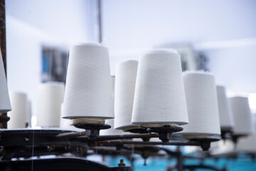 White Cotton Spools of Thread on the industrial knitting factory machine stand