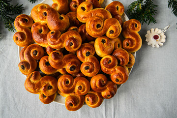 Big plate with pile of homemade Swedish saffron buns lussekatter on linen tablecloth .