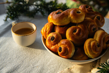 Plate with pile of homemade Swedish saffron buns lussekatter and cup of espresso coffee on linen...