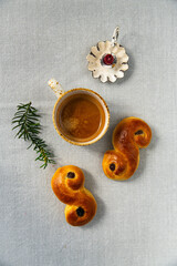 Homemade Swedish saffron buns lussekatter , cup of espresso coffee and candle on linen tablecloth .