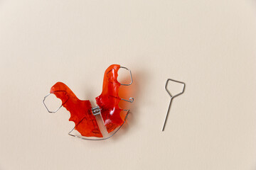 Red retainer or jaw expander on the background. Crooked teeth correction concept and bite...