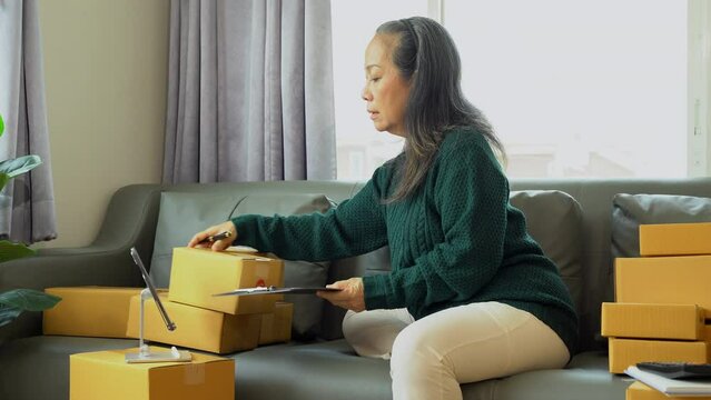 Startup small business entrepreneur or freelance using a laptop with box, checking orders from customers, matron runs an e-commerce business on websites and social media. 