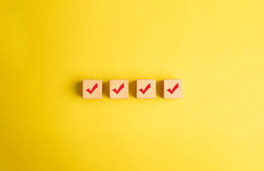Concept of selection. Red tick mark with red pen on wooden blocks on yellow background