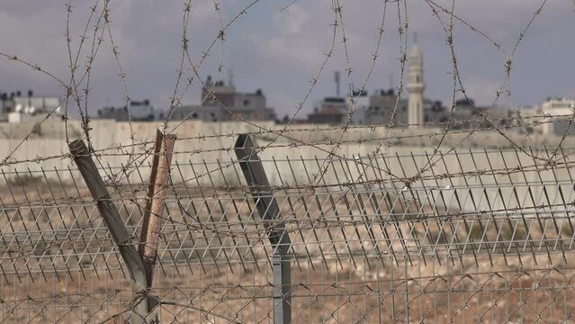 Separation wall and minaret in Ramallah, seen behind barbed wire, from the Jerusalem side, security measures in Israel