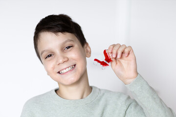 Boy smiling with tooth retainers in hand. Concept of crooked teeth correction and bite correction...