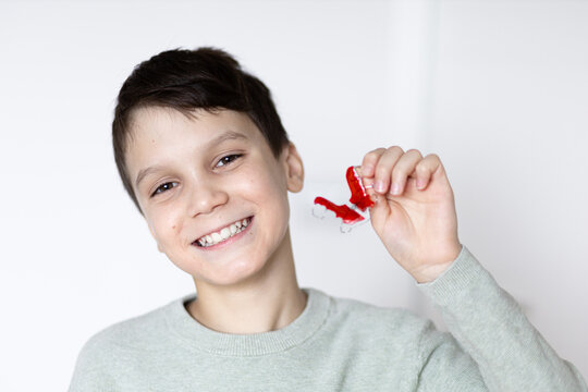 Boy smiling with tooth retainers in hand. Concept of crooked teeth correction and bite correction in children.