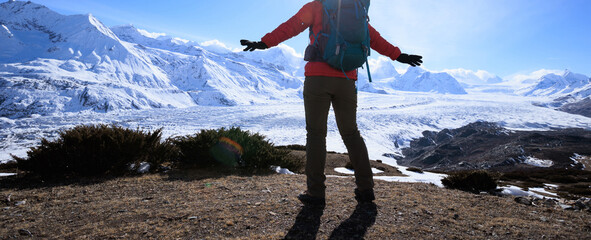 Woman hiker enjoy the view on mountain top cliff edge face to glacier mountains