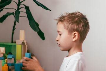 a boy plays with a multi-colored construction set in the form of geometric shapes in a bright room