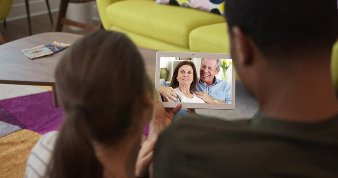 Millennial couple video chat with Caucasian senior parents over tablet computer