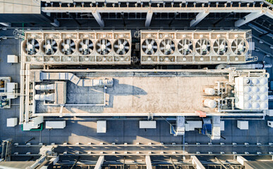 Fototapeta premium Aerial top down view of ventilation and air conditioning systems installed on the rooftop of a skyscraper in a developed business district