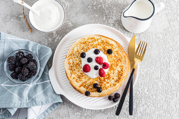 Top view of a serving table with traditional treats for the holiday of seeing off winter in Russia. pancakes, sour cream, milk, berries.