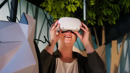 Smiling woman having fun wearing a virtual reality headset in the VR room during natural history...