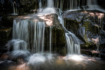 The waterfall flowing through mossy rocks and the water shot like a veil with a long exposure technique