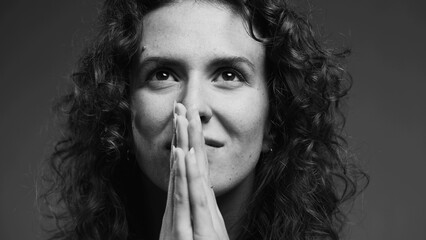 Spiritual 20s person feeling GRATITUDE and Godly devotion with eyes closed and hands clenched in...