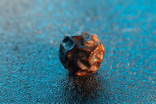 Black pepper spicy dried seed that looks like a space meteorite with a colorful background. Macro close-up photo.