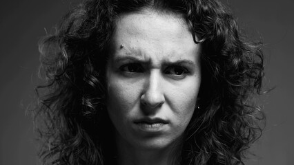 Serious concerned woman frowning and looking at camera in intense monochromatic black and white
