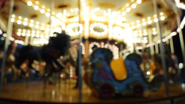 Defocused nighttime Christmas carousel spinning with warm lights