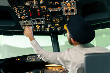 Fototapeta na wymiar Airplane cabin The pilot checks the plane's electronics by pressing the buttons Preparing the passenger liner for takeoff