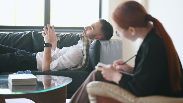 Lying down on the sofa. Man is on the therapy session with female psychologist.