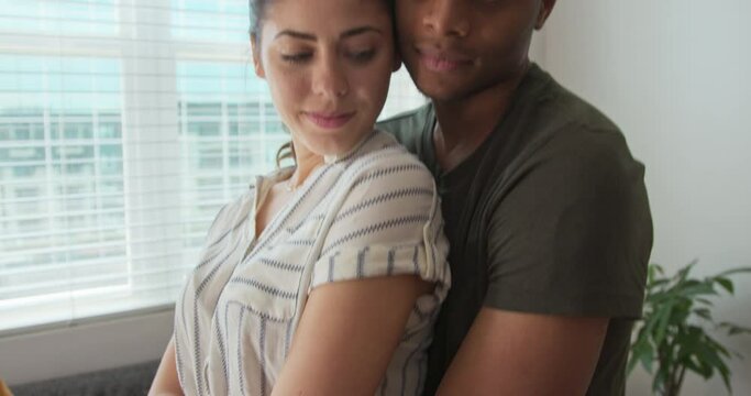 Close up portrait of millennial man and woman holding each other and looking at camera. African American and Caucasian couple at home in close-up. 4k slow motion handheld