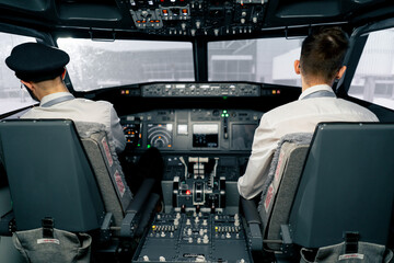 Airplane cabin Pilots check airplane electronics by pressing buttons Passenger airliner preparation for takeoff rear view flight simulator