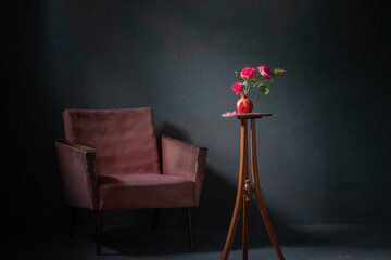 pink roses in pink vase with old armchair on background dark   wall