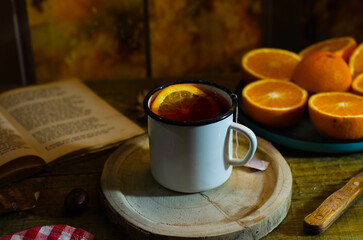 Cup of autumn tea with a book and yellow dry leaves near a window, copy space. Hot drink for autumn cold rainy days. Hygge concept, autumn mood.