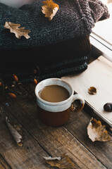 Large Cup of cappuccino on vintage brown background. Autumn, fall leaves, hot steaming cup of coffee and a warm scarf on wooden table background. Seasonal, morning coffee, Sunday relaxing and still l