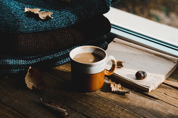 Large Cup of cappuccino on vintage brown background. Autumn, fall leaves, hot steaming cup of coffee and a warm scarf on wooden table background. Seasonal, morning coffee, Sunday relaxing and still l