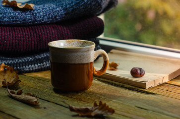 Large Cup of cappuccino on vintage brown background. Autumn, fall leaves, hot steaming cup of coffee and a warm scarf on wooden table background. Seasonal, morning coffee, Sunday relaxing and still l