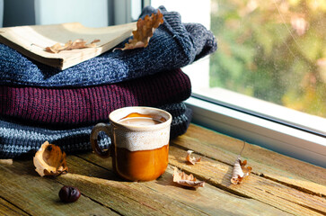 Large Cup of cappuccino on vintage brown background. Autumn, fall leaves, hot steaming cup of coffee and a warm scarf on wooden table background. Seasonal, morning coffee, Sunday relaxing and still l