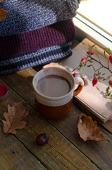 Large Cup of cappuccino on vintage brown background. Autumn, fall leaves, hot steaming cup of coffee and a warm scarf on wooden table background. Seasonal, morning coffee, Sunday relaxing and still l